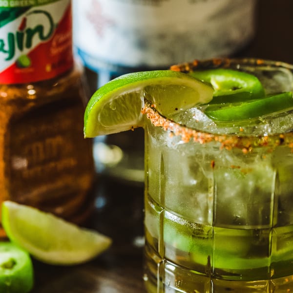 Close-up of a Colonial Bar & Grill cocktail with lime, jalapeños, and a spiced rim.